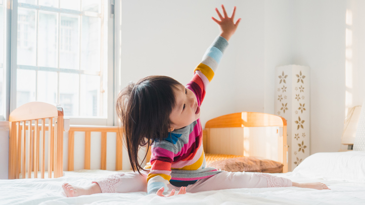 3-year-old sleep regression, little toddler girl awake and playing on the bed