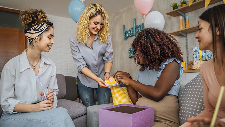 baby shower etiquette, new mom opening gifts with friends at a shower