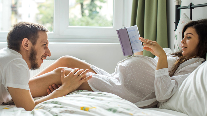 pregnant woman reading in bed with partner, decreased sex drive during pregnancy