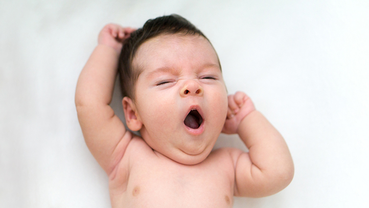 drowsy but awake, sleepy baby yawning in crib