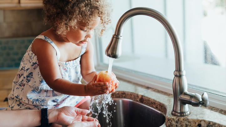 food poisoning in young children, little girl washing fruit at the sink