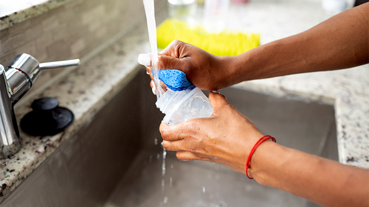 mom holding baby, breast pump and bottles, things to know about cleaning your breast pump