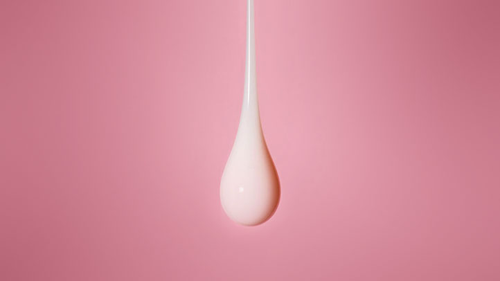 leaking breasts postpartum, white drop on pink background