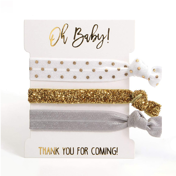 Three-pack of polka dot, sparkly gold and gray hair ties wrapped around cardstock with"oh baby!" written at the top and "thank you for coming! at the bottom in gold
