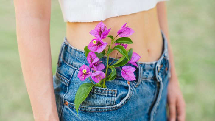 ovulation symptoms, woman with flowers in her front jeans pocket