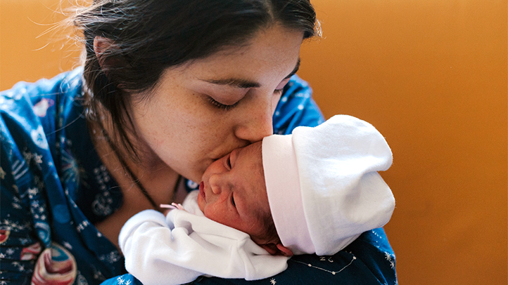 postpartum bonding, mother kissing new baby