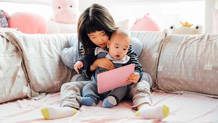 how to prepare your toddler for room sharing, toddler girl showing baby sibling a toy