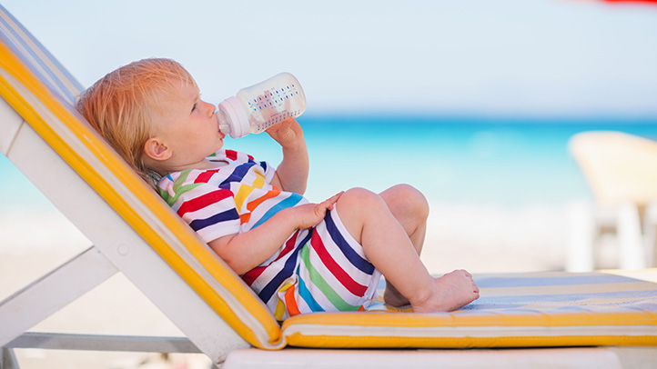 toddler drinking bottle of water on the beach