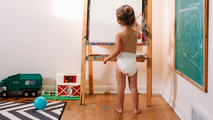 toddler undressing and taking clothes and diaper off, little girl painting at easel in diaper